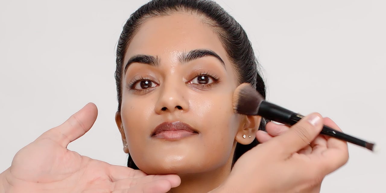 Makeup artist applying foundation to complement a brown smokey eye